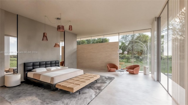 bedroom with concrete floors, access to outside, and floor to ceiling windows