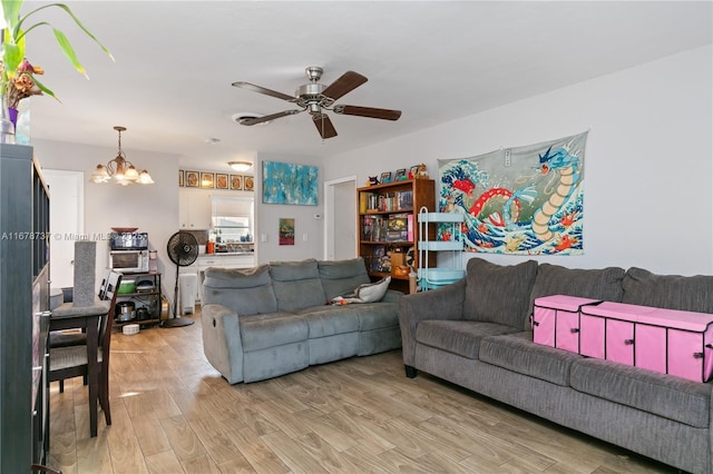 living room with ceiling fan with notable chandelier and light hardwood / wood-style flooring