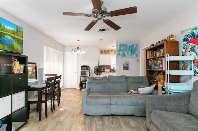 living room featuring ceiling fan with notable chandelier and light hardwood / wood-style flooring