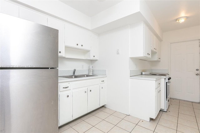 kitchen with white range oven, white cabinetry, sink, and stainless steel refrigerator