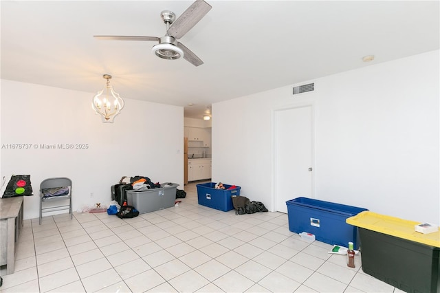 interior space with light tile patterned flooring and ceiling fan with notable chandelier