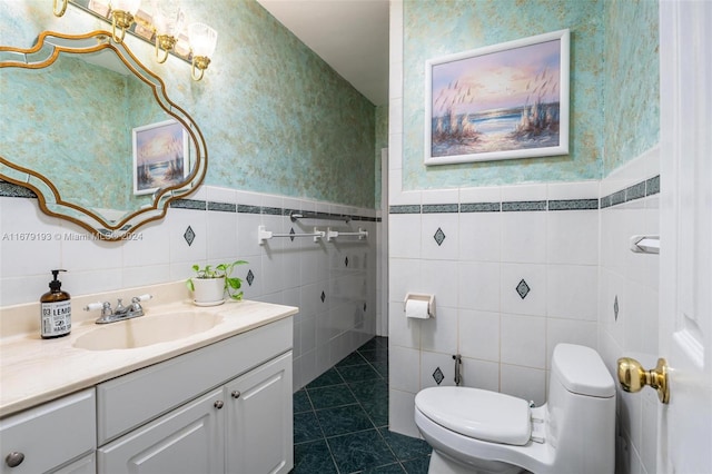 bathroom with toilet, vanity, tile patterned floors, and tile walls