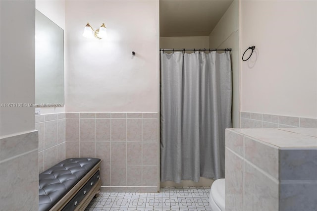 bathroom with toilet, tile patterned floors, tile walls, and curtained shower