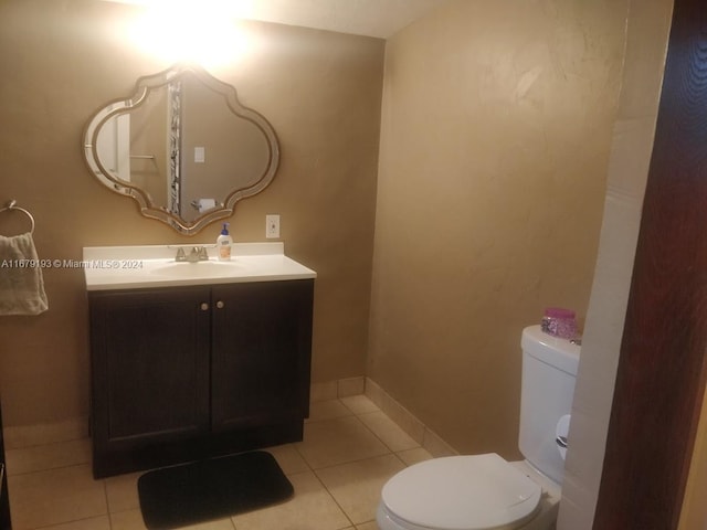 bathroom with toilet, vanity, and tile patterned floors