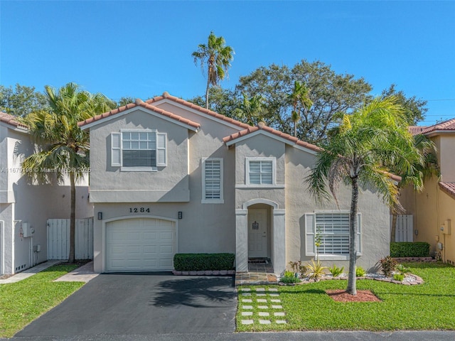 mediterranean / spanish home with a garage and a front lawn