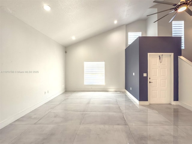 empty room with ceiling fan, high vaulted ceiling, and a textured ceiling