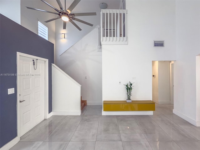 tiled entryway with a towering ceiling and ceiling fan