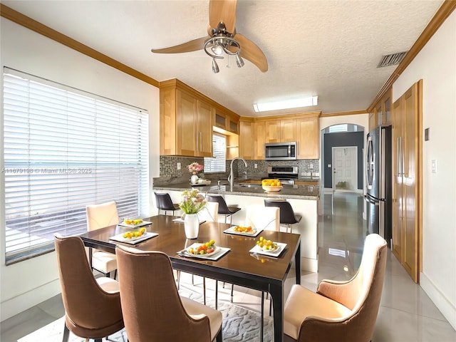 kitchen featuring light tile patterned flooring, tasteful backsplash, kitchen peninsula, crown molding, and appliances with stainless steel finishes