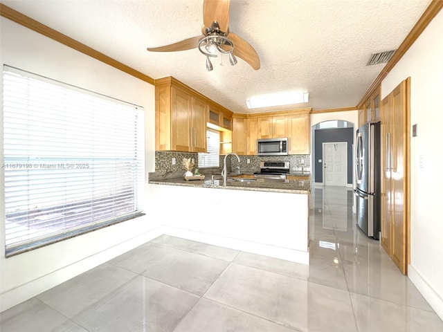 kitchen with kitchen peninsula, a textured ceiling, stainless steel appliances, ornamental molding, and sink