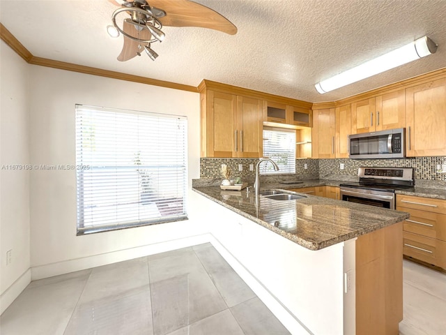 kitchen featuring stainless steel appliances, sink, light tile patterned floors, kitchen peninsula, and dark stone counters