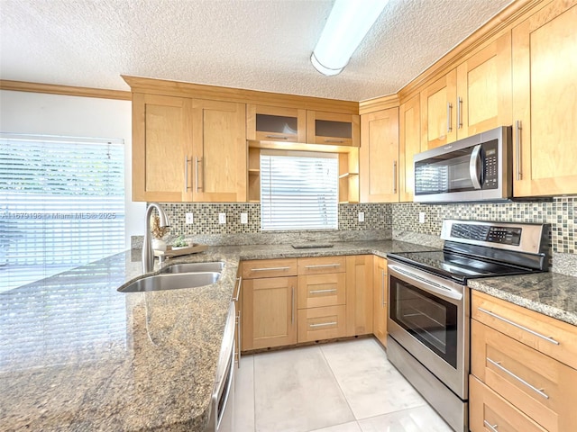 kitchen with a textured ceiling, appliances with stainless steel finishes, dark stone countertops, and sink