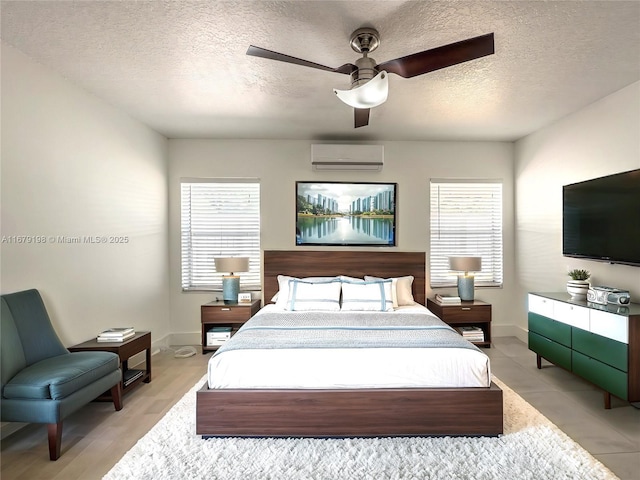 bedroom with multiple windows, a textured ceiling, ceiling fan, and a wall mounted AC