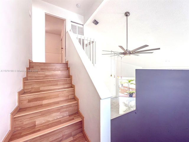 stairs featuring ceiling fan