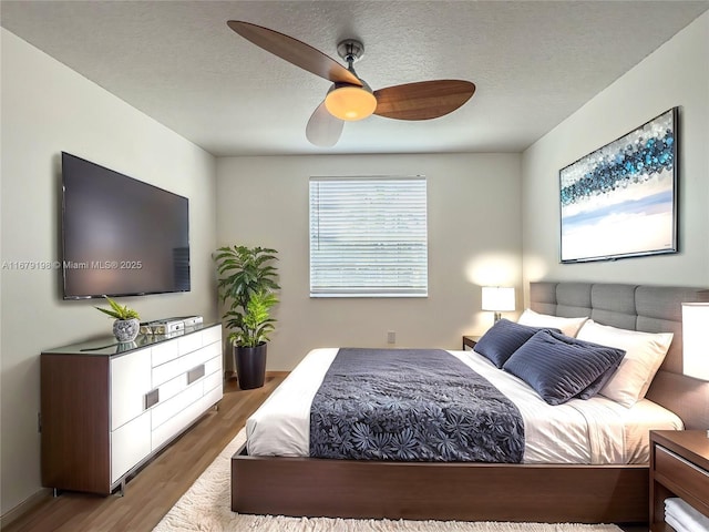 bedroom featuring a textured ceiling, ceiling fan, and wood-type flooring