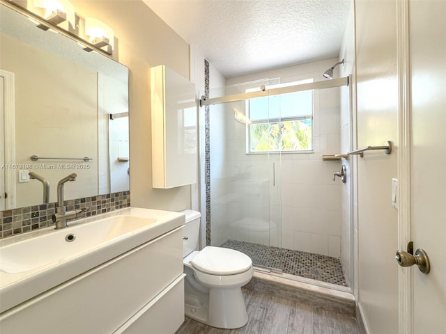 bathroom featuring toilet, a textured ceiling, hardwood / wood-style floors, a shower with shower door, and vanity