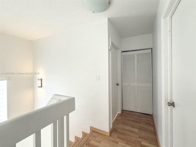 corridor with light hardwood / wood-style floors and a textured ceiling