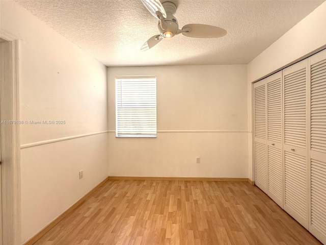 unfurnished bedroom featuring ceiling fan, light hardwood / wood-style flooring, a closet, and a textured ceiling