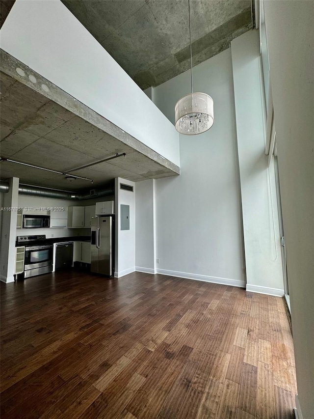 unfurnished living room with a towering ceiling, a chandelier, and dark hardwood / wood-style floors