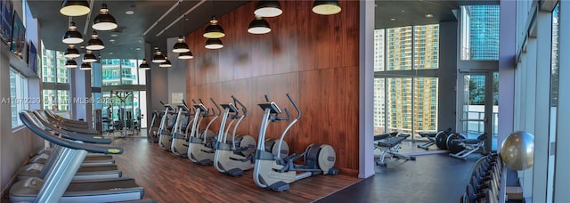 exercise room with wooden walls, a towering ceiling, and dark wood-type flooring