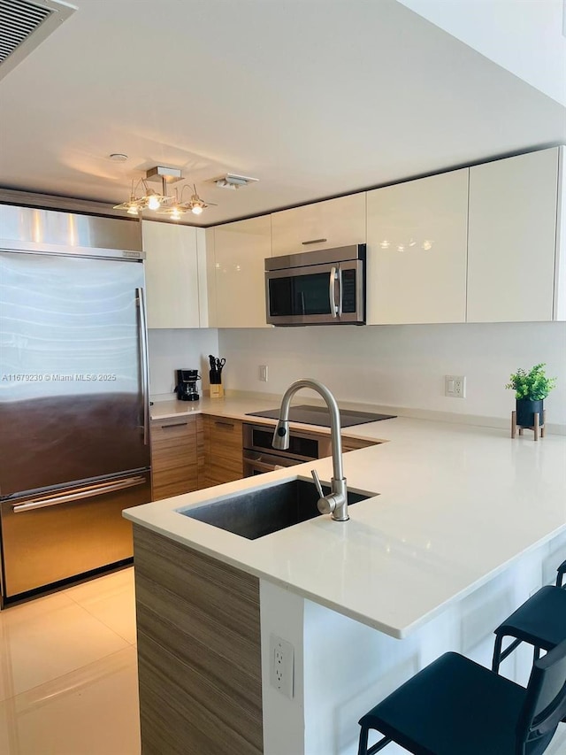 kitchen with a kitchen breakfast bar, kitchen peninsula, white cabinetry, and stainless steel appliances