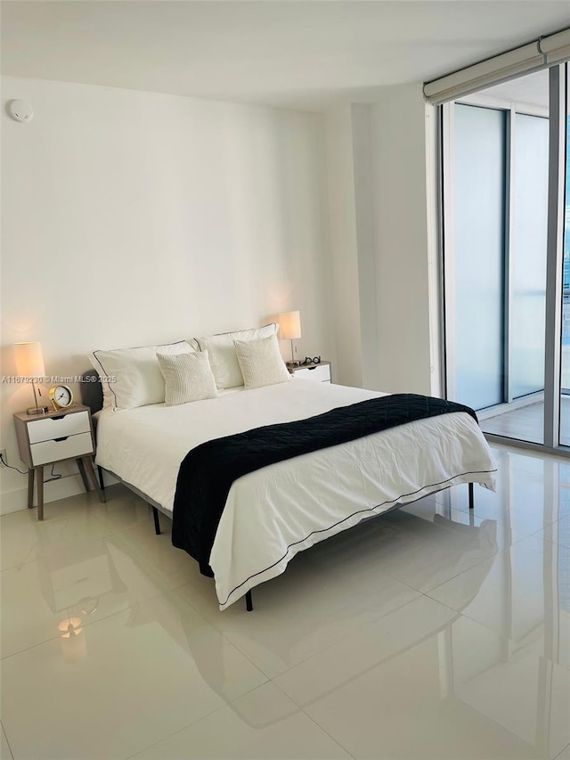 bedroom featuring access to exterior, light tile patterned floors, and a wall of windows