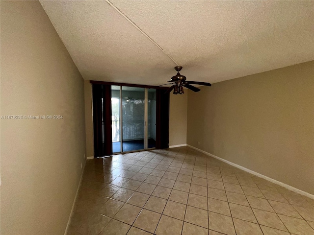 unfurnished room with a textured ceiling, light tile patterned floors, and ceiling fan