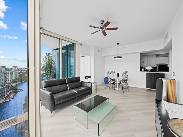 living room with a water view, light wood-type flooring, and ceiling fan