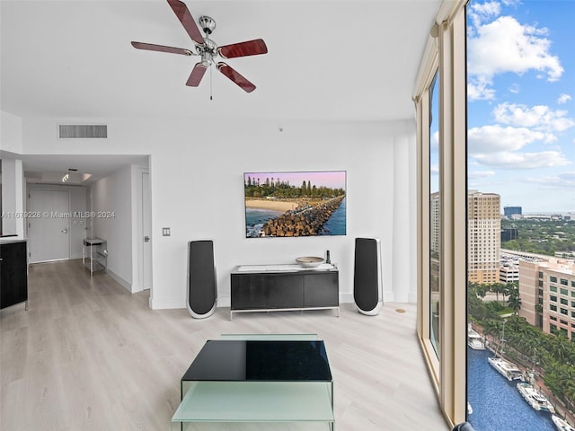 living room featuring light hardwood / wood-style flooring, a water view, and ceiling fan