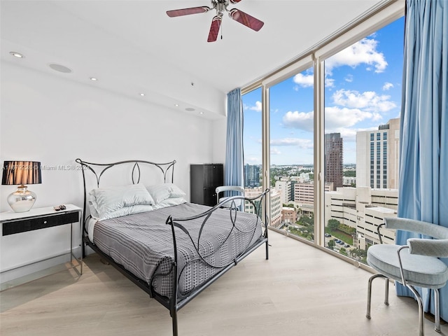 bedroom with light hardwood / wood-style floors, floor to ceiling windows, and ceiling fan