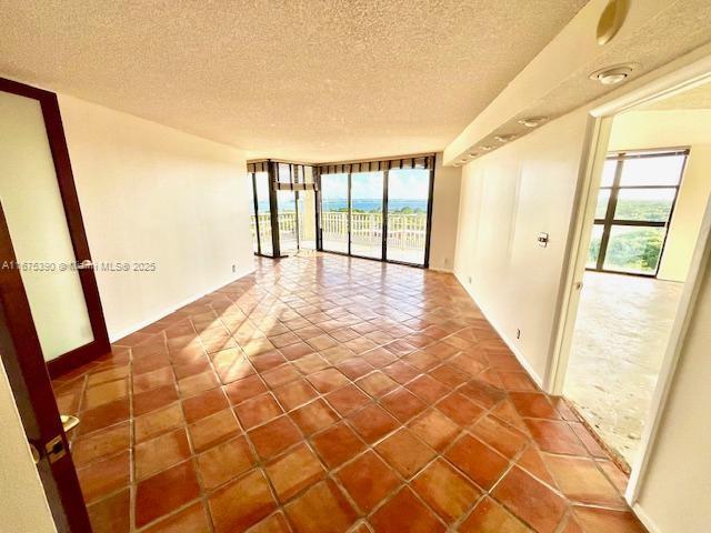 empty room featuring a water view, a textured ceiling, and a wealth of natural light