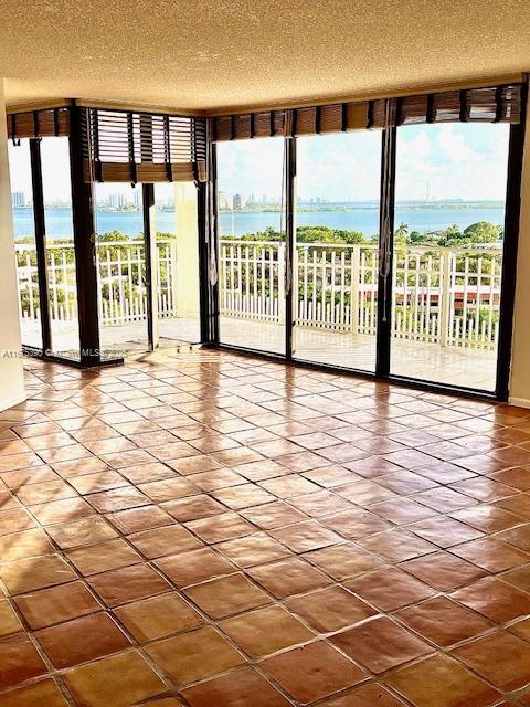 empty room with a textured ceiling and a water view