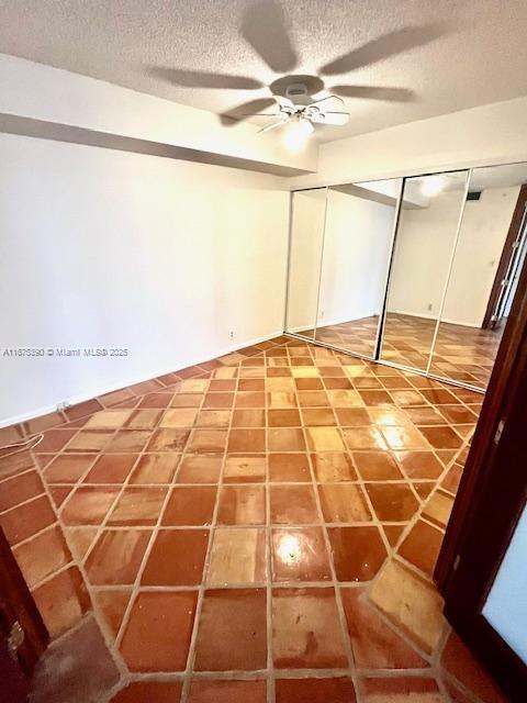 unfurnished bedroom featuring ceiling fan, a textured ceiling, and a closet