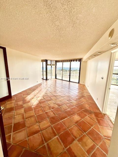 empty room featuring a textured ceiling and a wall of windows