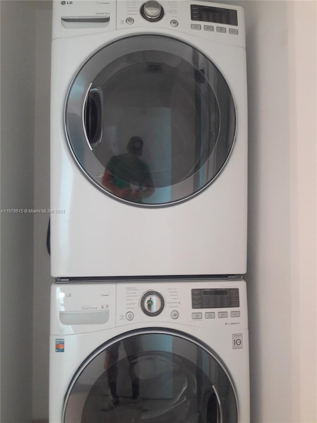 clothes washing area with stacked washing maching and dryer