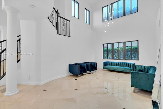 living room with a towering ceiling, decorative columns, and a wealth of natural light