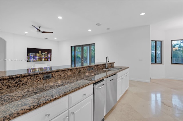 kitchen featuring sink, dishwasher, dark stone counters, and white cabinets