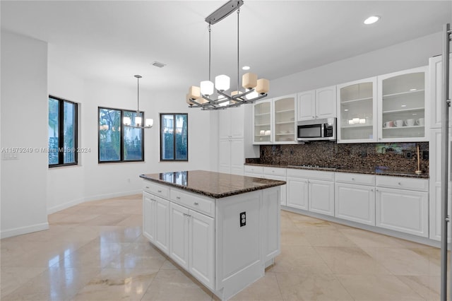 kitchen with white cabinetry, a healthy amount of sunlight, dark stone counters, and pendant lighting