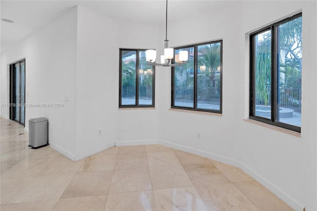 unfurnished dining area featuring an inviting chandelier and a healthy amount of sunlight