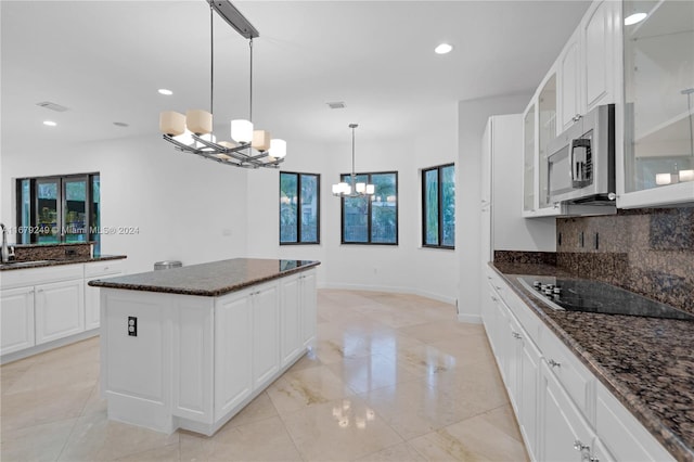 kitchen with an inviting chandelier, black electric cooktop, white cabinetry, and a wealth of natural light