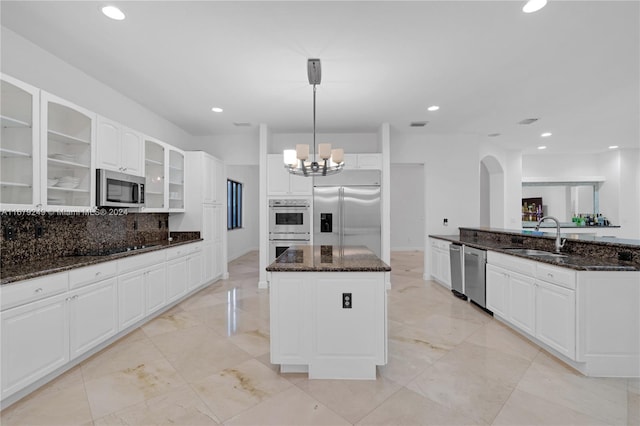 kitchen with appliances with stainless steel finishes, decorative light fixtures, white cabinets, and dark stone countertops