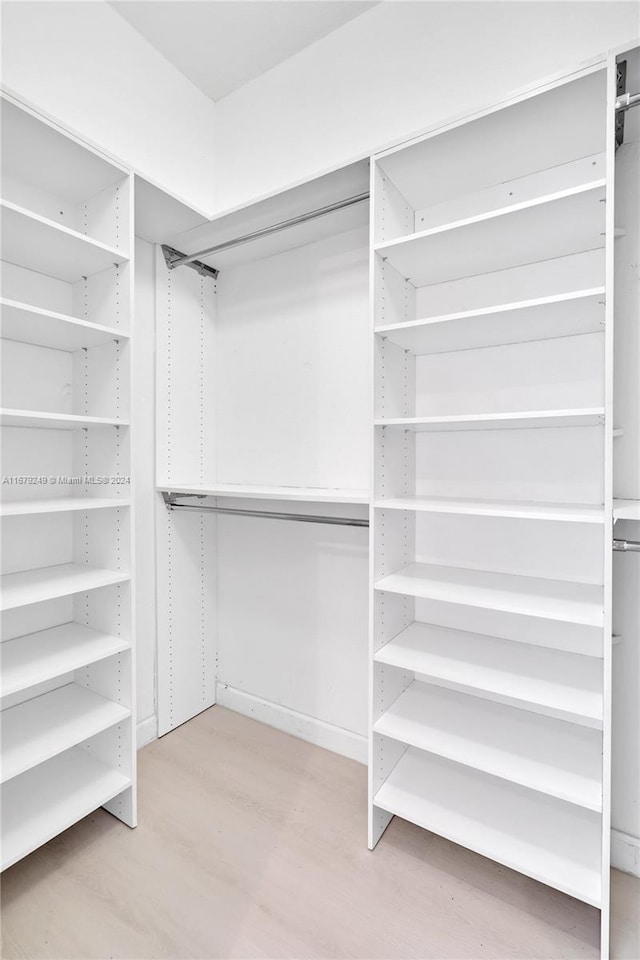 walk in closet with light hardwood / wood-style floors