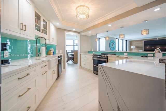 kitchen with backsplash, appliances with stainless steel finishes, white cabinetry, light stone countertops, and pendant lighting