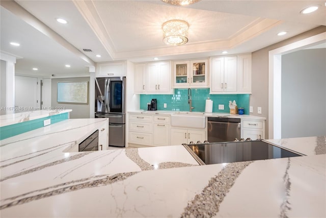 kitchen with light stone countertops, appliances with stainless steel finishes, backsplash, a raised ceiling, and white cabinets