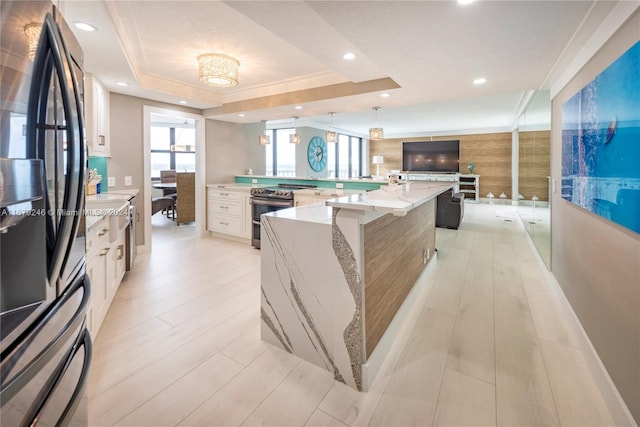 kitchen with light stone countertops, electric stove, a raised ceiling, a large island, and black refrigerator