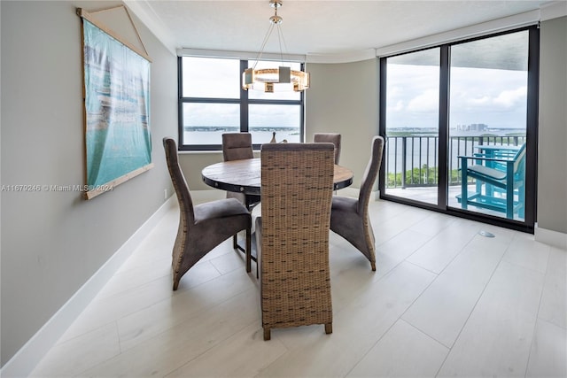 dining area with floor to ceiling windows, a notable chandelier, a water view, and plenty of natural light