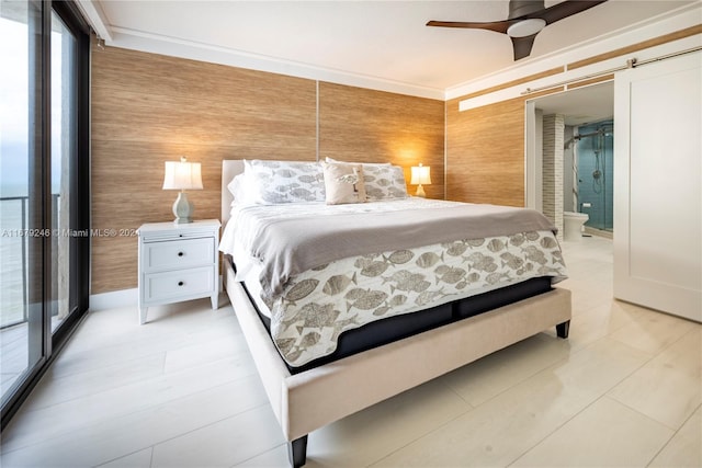 bedroom with ensuite bathroom, a barn door, wooden walls, and ceiling fan