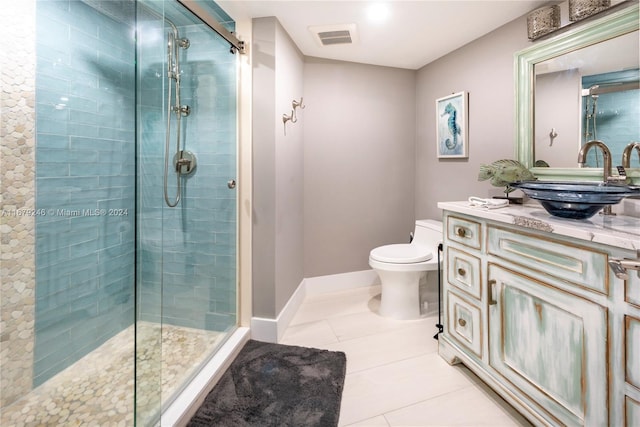 bathroom with a shower with door, vanity, toilet, and tile patterned flooring