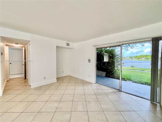 spare room featuring a water view and light tile patterned floors