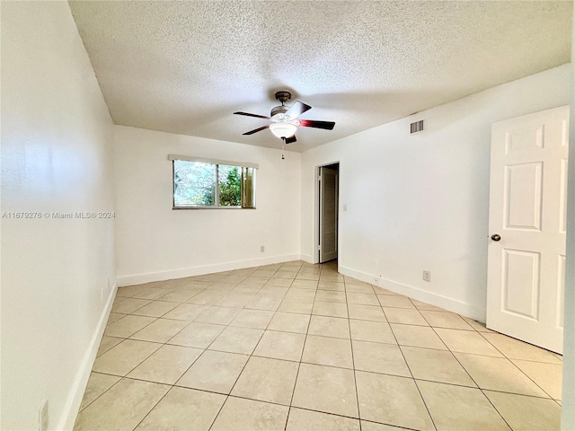 spare room with ceiling fan, a textured ceiling, and light tile patterned floors