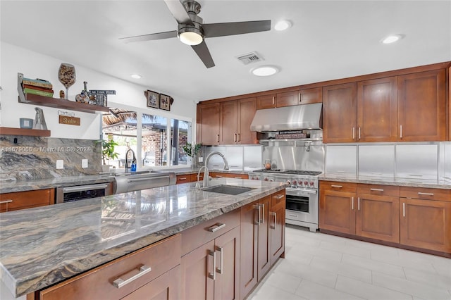 kitchen with light stone countertops, sink, ceiling fan, high end stainless steel range, and decorative backsplash